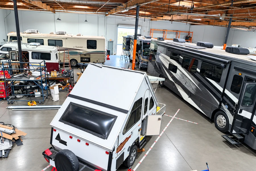A-frame camper trailer in the El Toro RV Service bay beside a Class A motorhome