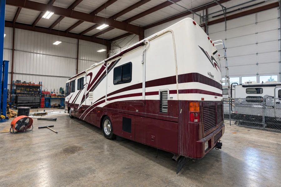 Burgundy and white Class A motorhome in an indoor service bay