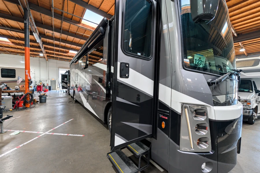 Gray Class A motorhome with entry steps extended in the service bay