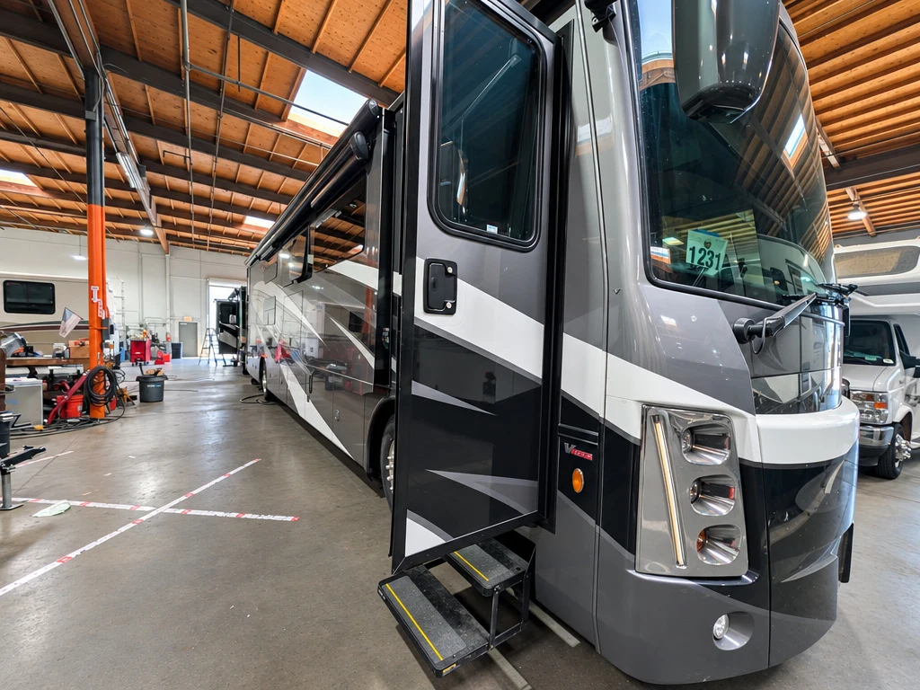 Gray Class A motorhome with entry steps extended in the service bay