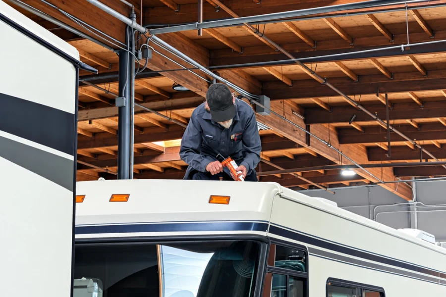 Technician inspecting the roof and front cap of a Class A motorhome