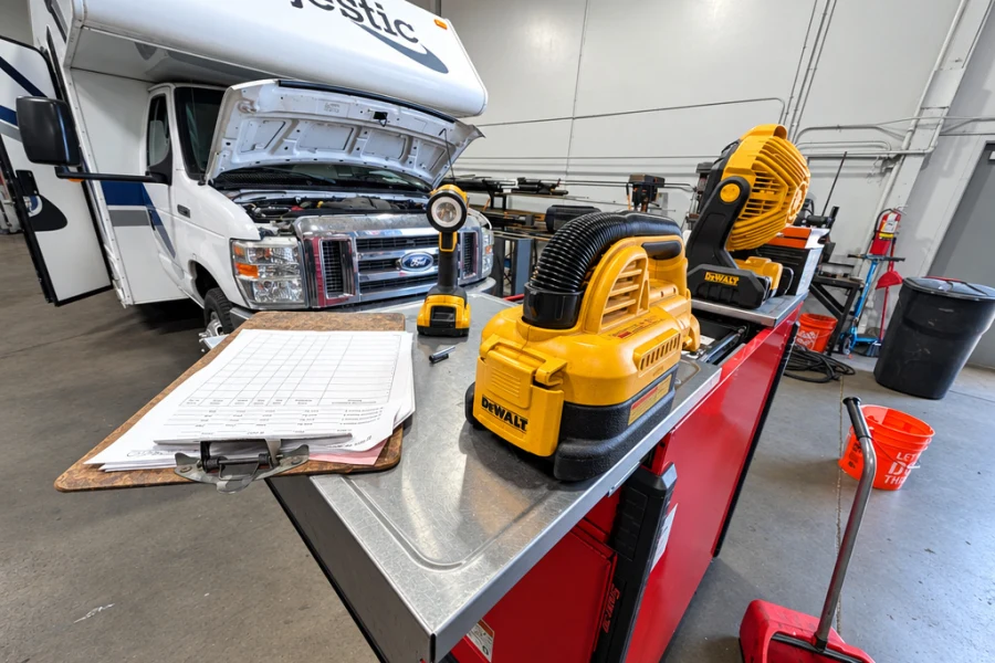 Class C motorhome with the hood open and a service write-up on the cart