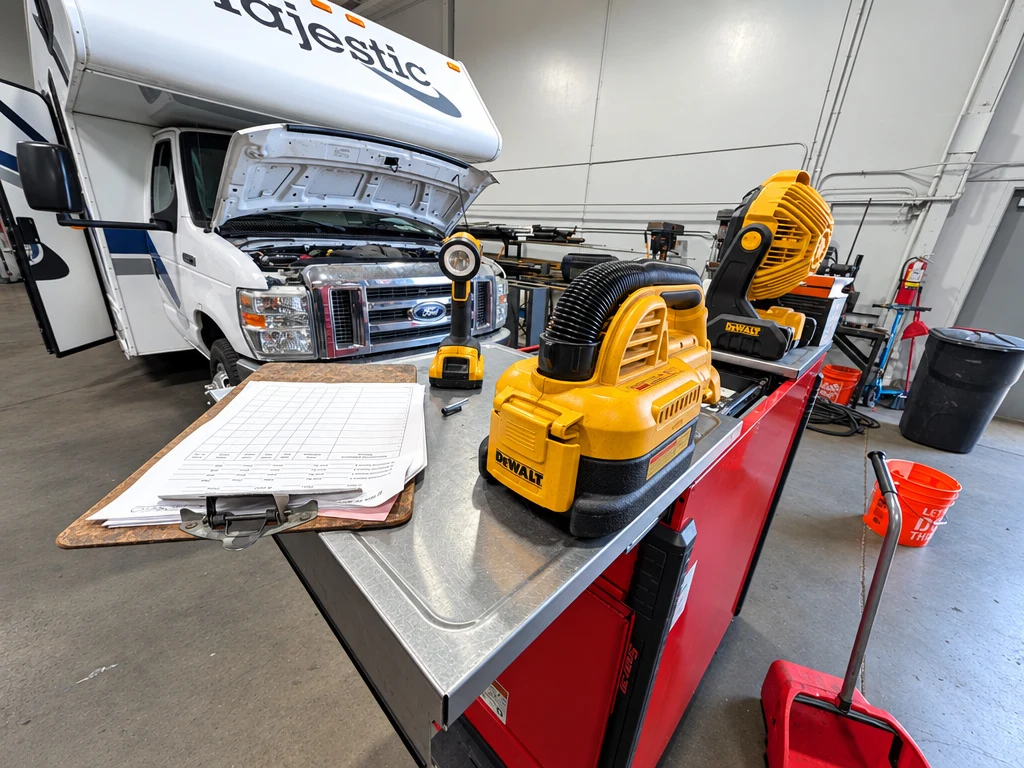 Class C motorhome with the hood open and a service write-up on the cart