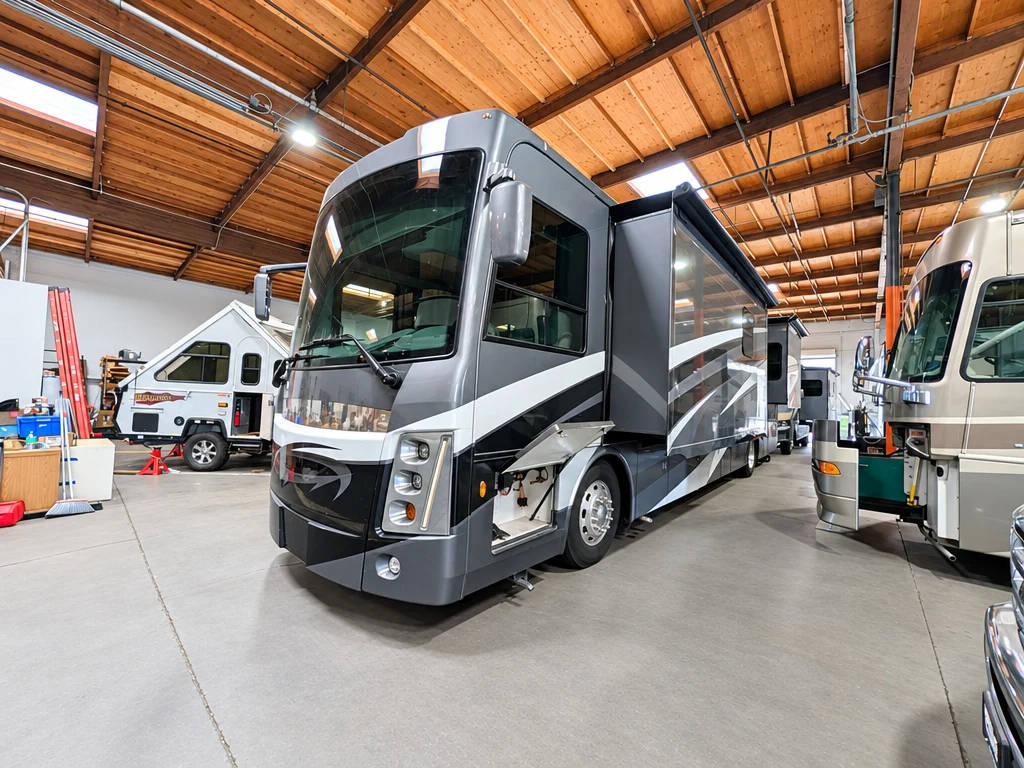 Front cap and graphics of a gray Class A motorhome in the El Toro shop