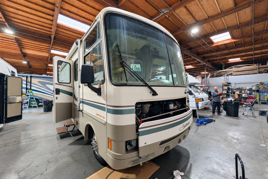 Older Class A motorhome with its front cap removed for body repair