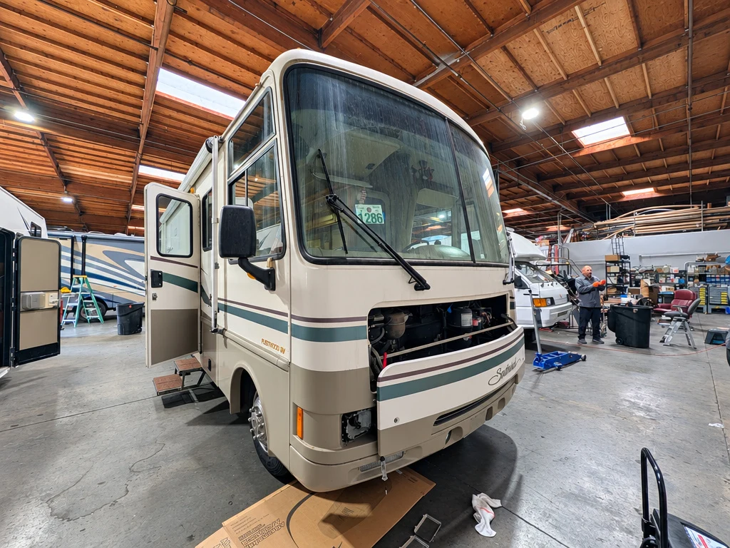 Older Class A motorhome with its front cap removed for body repair