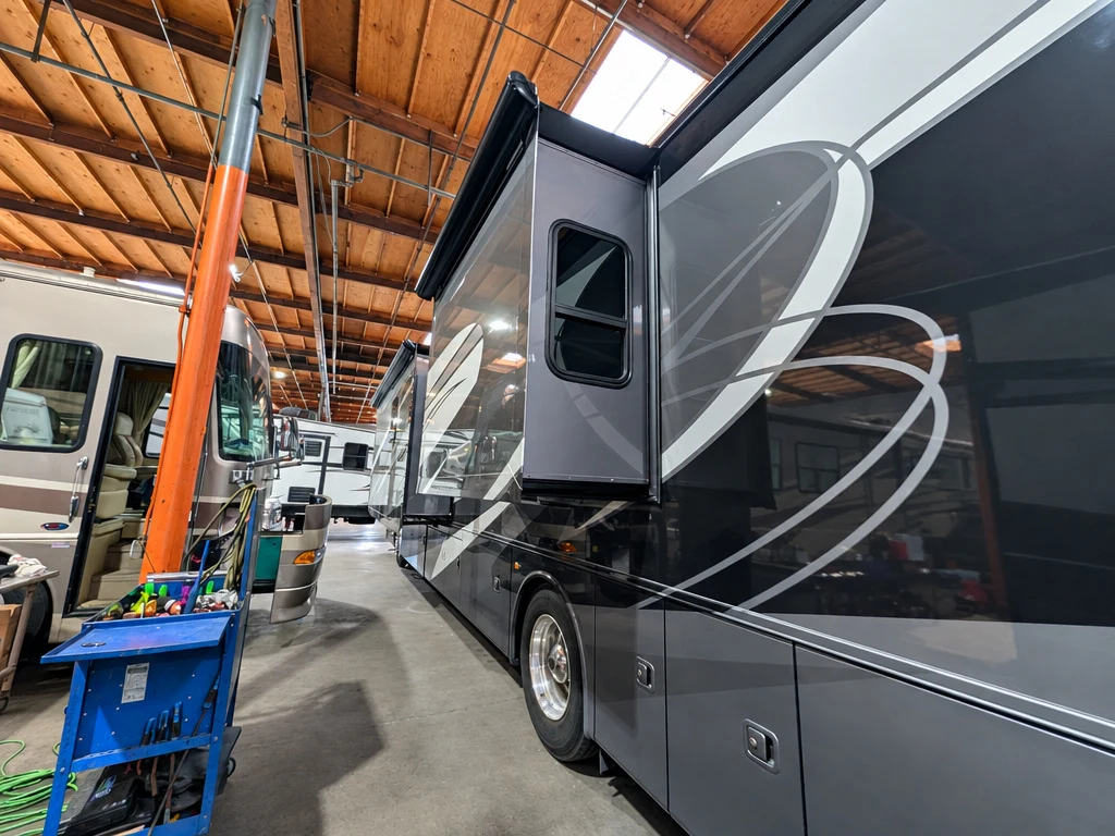 Large slide-out on the side of a gray Class A motorhome in the El Toro shop