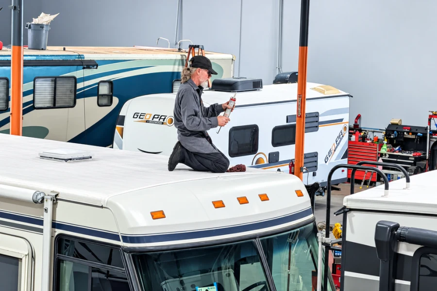 Technician checking roof seals on top of a Class C motorhome at El Toro RV Service
