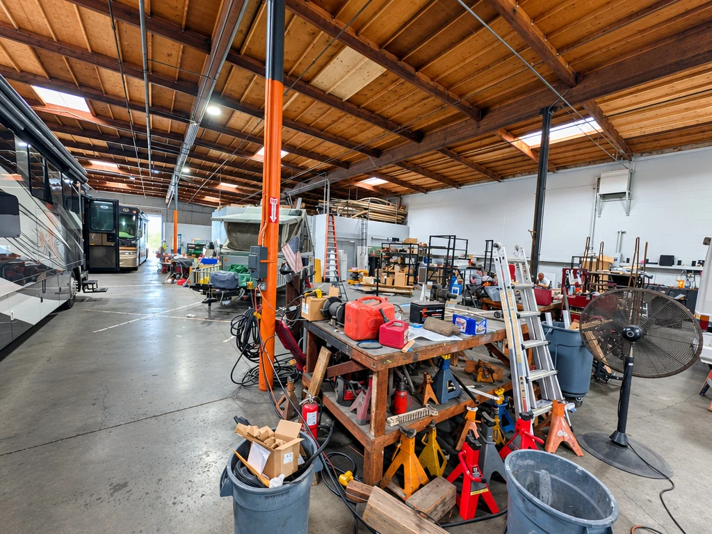 Technician workbenches and tools beside motorhomes in the El Toro RV shop
