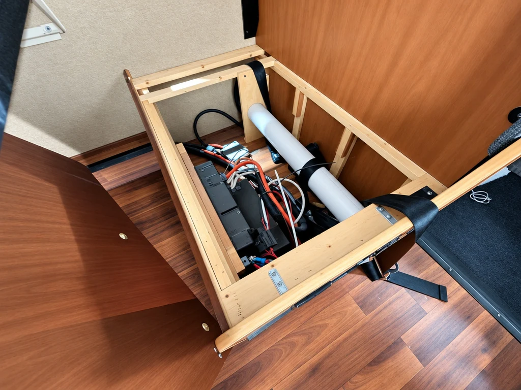 RV under-bed compartment opened to reach batteries and wiring