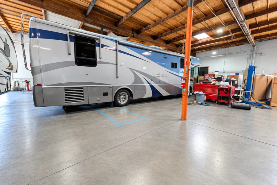 Silver Class A motorhome beside a lift in the El Toro RV Service shop