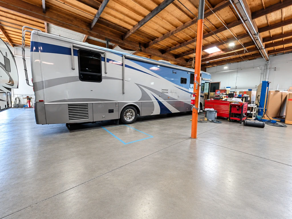 Silver Class A motorhome beside a lift in the El Toro RV Service shop