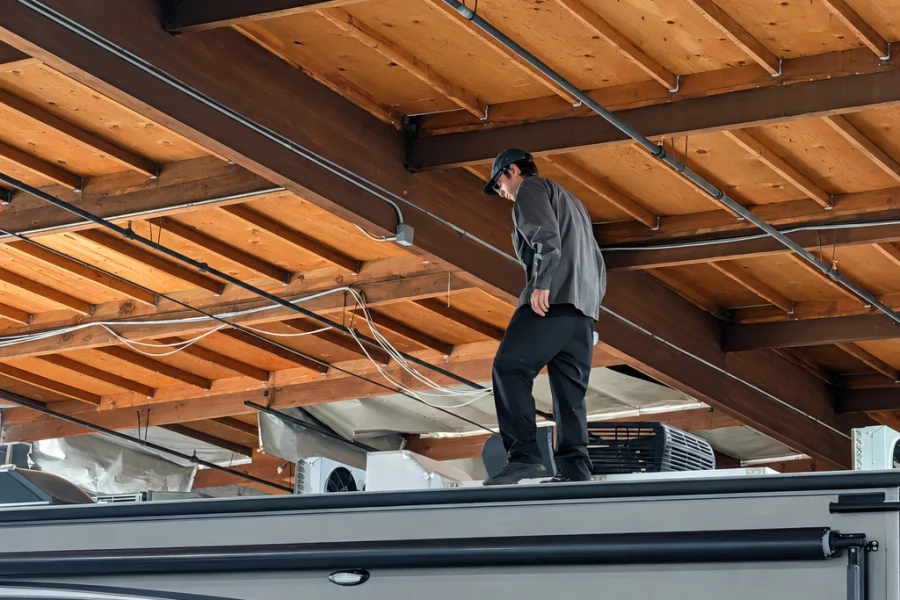 Technician working on top of a tall motorhome inside the El Toro RV shop